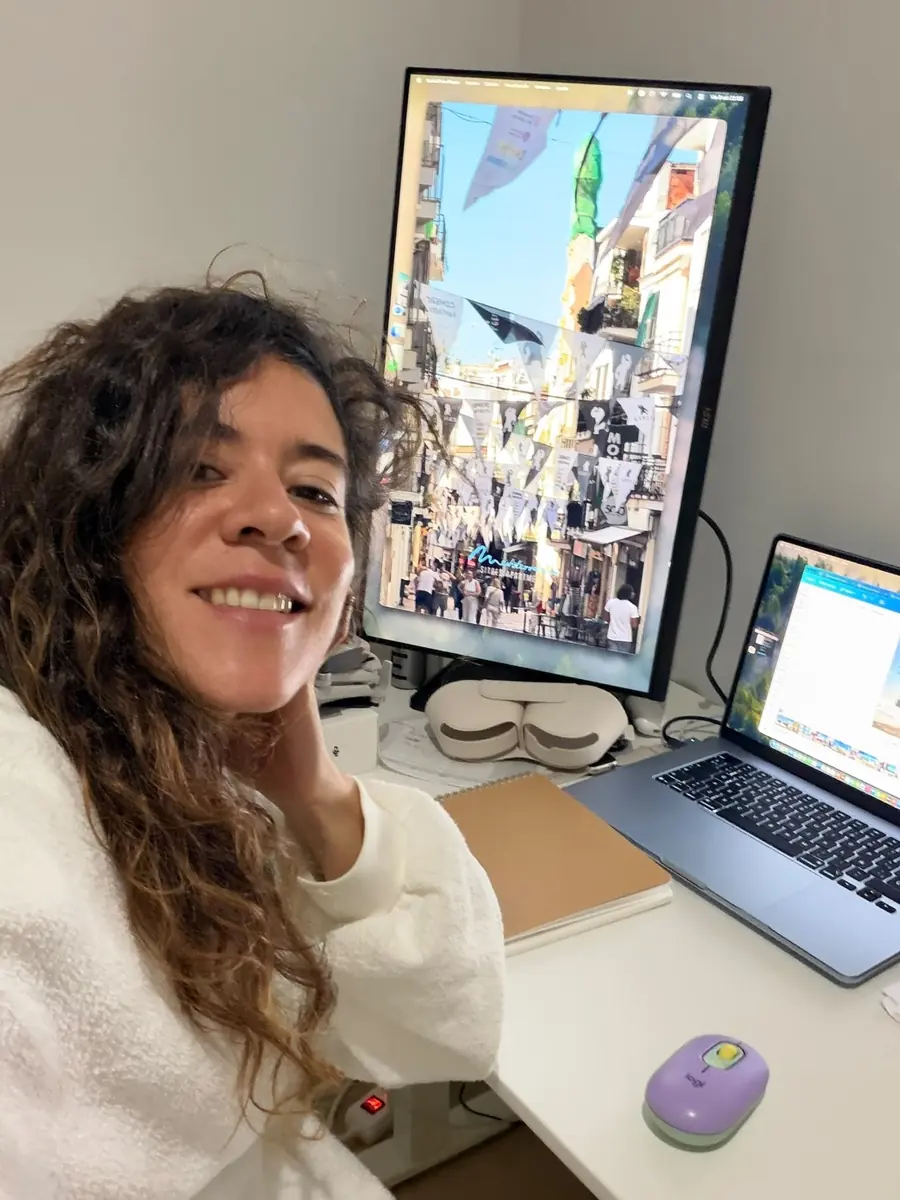 Eli smiling at her desk, editing a Sitges reel on a vertical screen